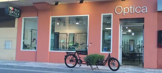 The terracotta-coloured front of Ole Optica on Calle Antonio Ferrándis in Nerja, with a Danish cargo bike by the door
